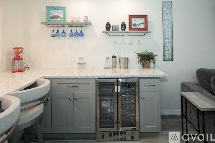 A kitchen with a wine cooler and a shelf with bottles on it.