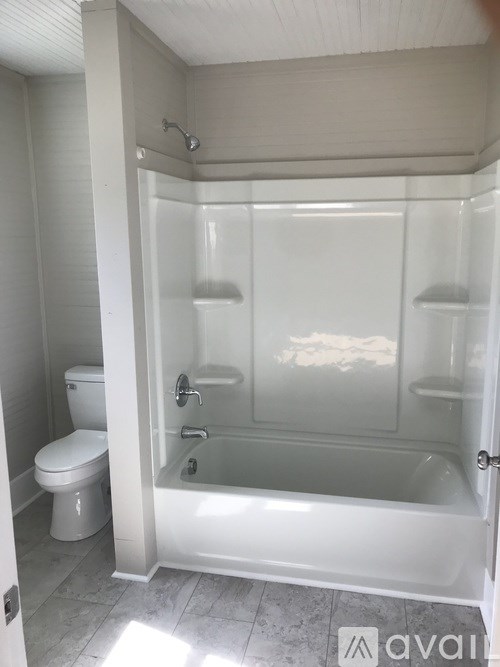A white bathroom with a toilet, tub, and shower.