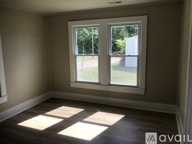 A room with a large window and wooden flooring.