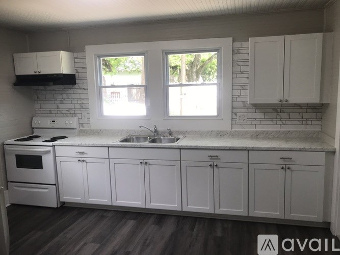 A kitchen with white cabinets and a brick wall.