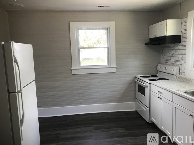 A kitchen with white appliances and a window.