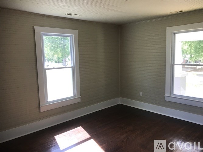 A room with two windows and wooden floors.