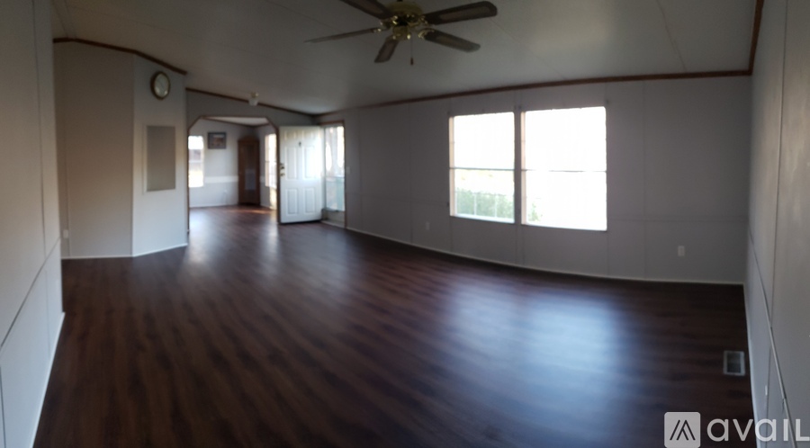 A spacious room with wooden flooring and a ceiling fan.