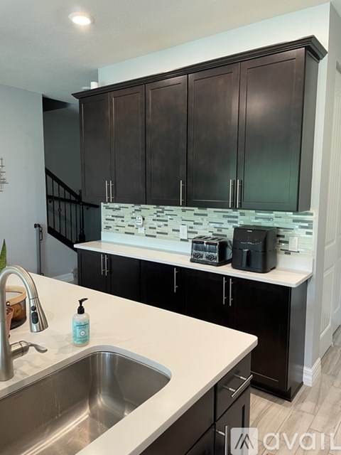 A kitchen with a sink and black cabinets.