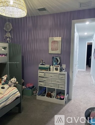 A child's bedroom with a bed, dresser, and a purple wall.