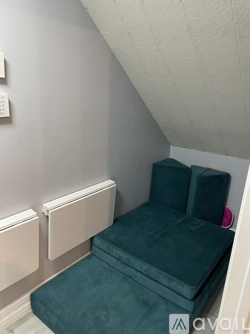 A green sofa with a grey wall behind it.