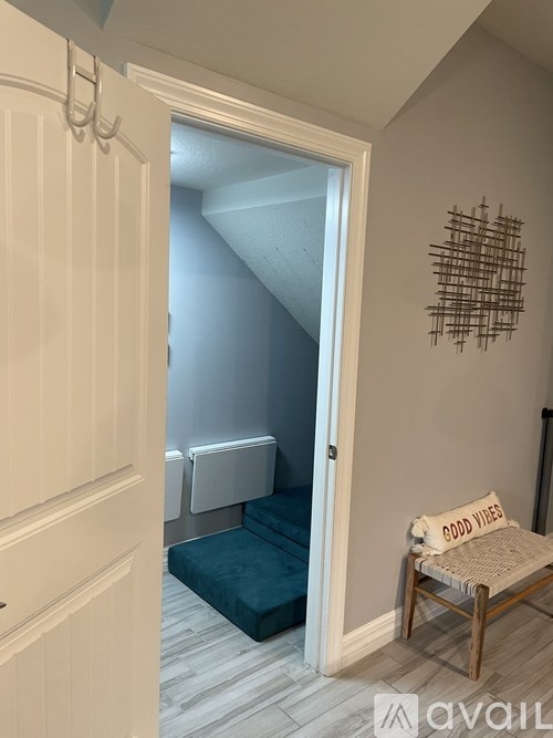 A room with a white door, a chair with a blanket on it, and a wall hanging.