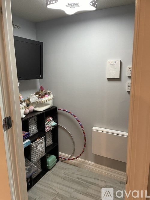 A room with a TV, shelves, and a wall-mounted heater.