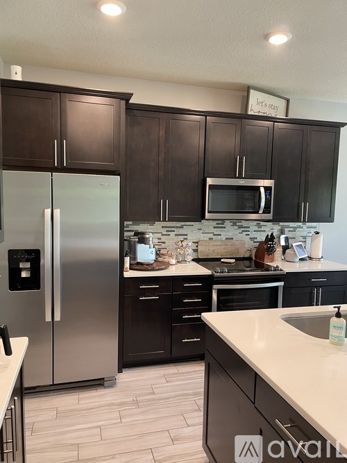 A kitchen with a refrigerator, microwave, and oven.