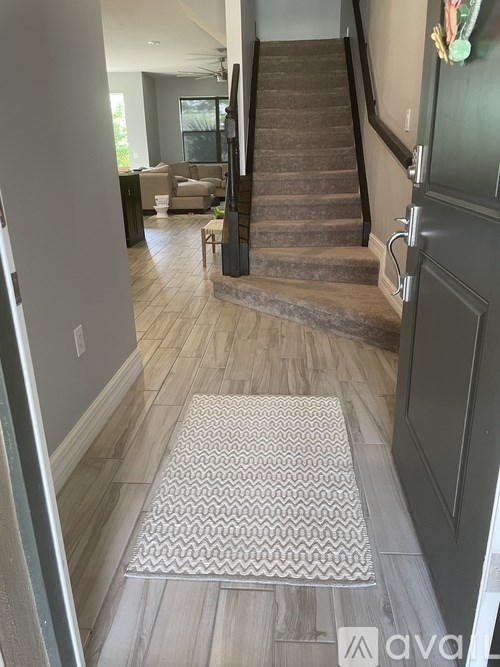 A hallway with a staircase and a rug on the floor.