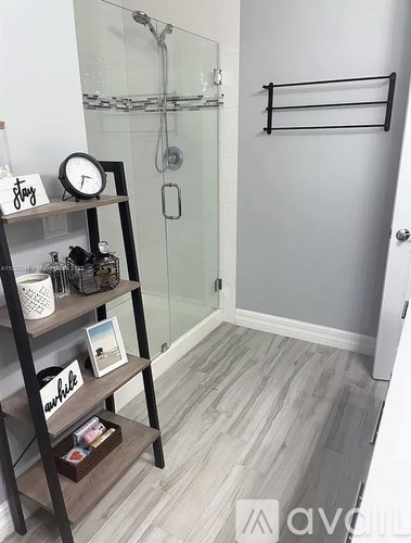 A bathroom with a glass shower door and a wooden shelf with decorative items.