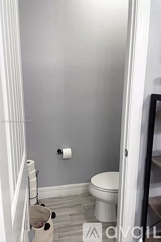 A bathroom with a toilet, a towel rack with towels and a roll of toilet paper.