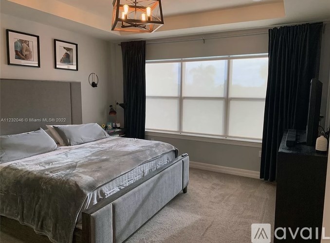 A bedroom with a large bed and a window with black curtains.