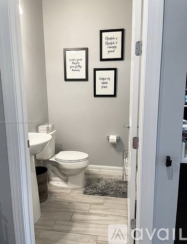 A bathroom with a toilet and two pictures on the wall.