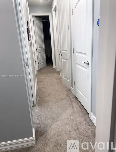 A hallway with white doors and carpeted floor.