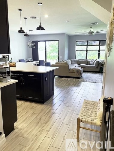 A kitchen with black cabinets and a white island.