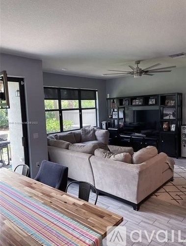 A living room with a couch, a television, and a ceiling fan.