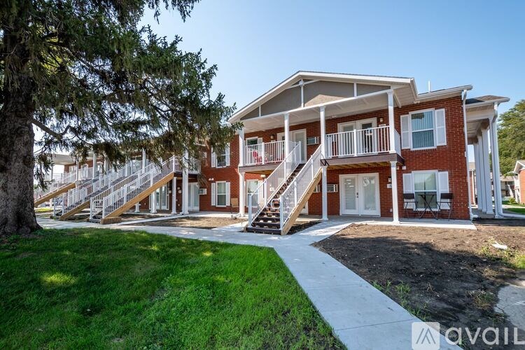 A red brick house with a white balcony and stairs leading to the front door.