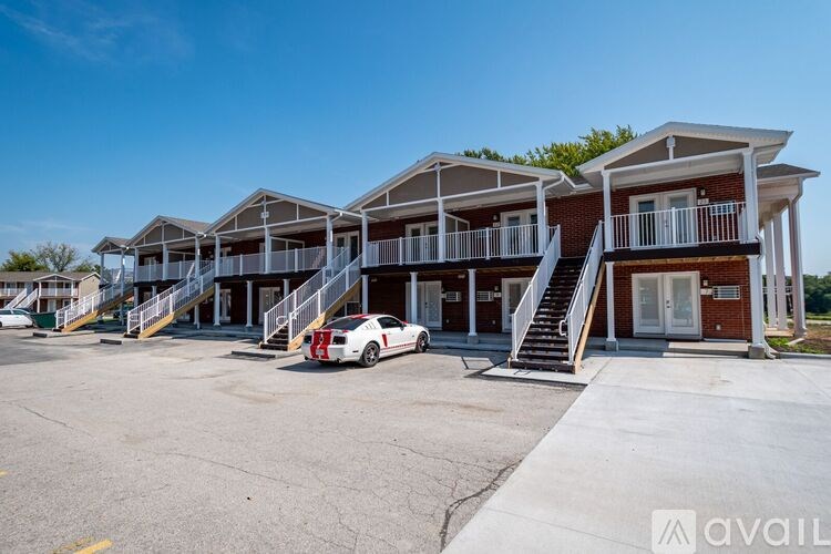 A white car is parked in front of a building with a sign that reads "available.".
