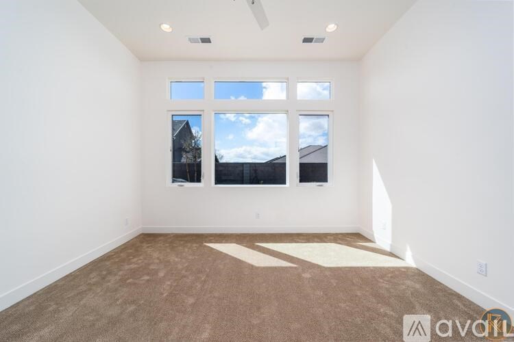A room with a carpeted floor and a window showing a view of the sky and a building.