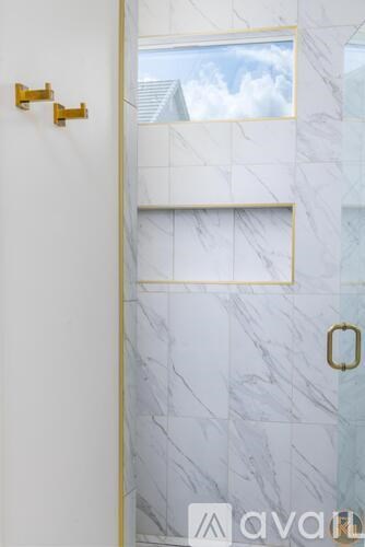 A white marble bathroom with a gold towel rack and a gold handle.