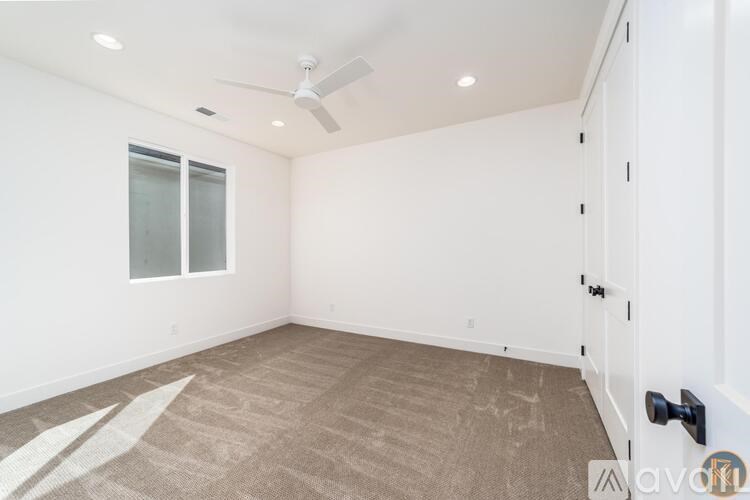 A room with a carpeted floor and a ceiling fan.