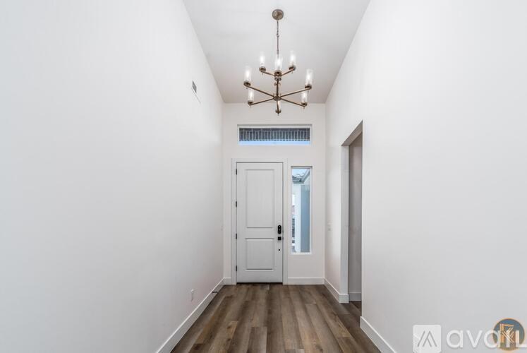 A hallway with a chandelier and a white door.