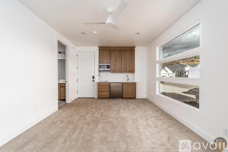 A spacious kitchen with wooden cabinets and a white ceiling fan.