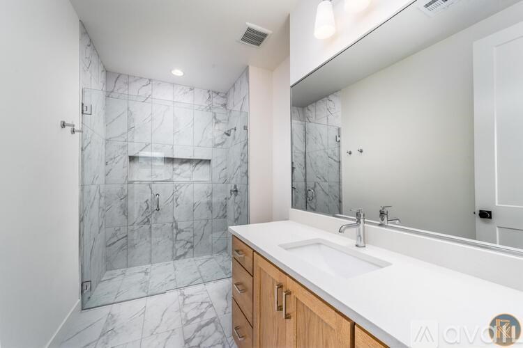 A bathroom with a marble tile shower and a white countertop.
