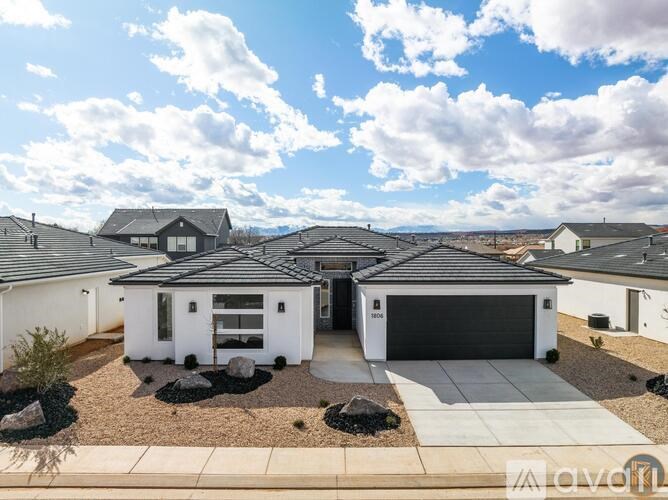 A white house with a black roof is surrounded by other similar houses.