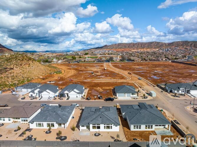 A housing development with a large open field in the foreground and houses with grey roofs.