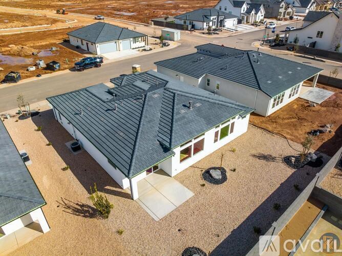 A large house with a grey roof is surrounded by smaller houses.