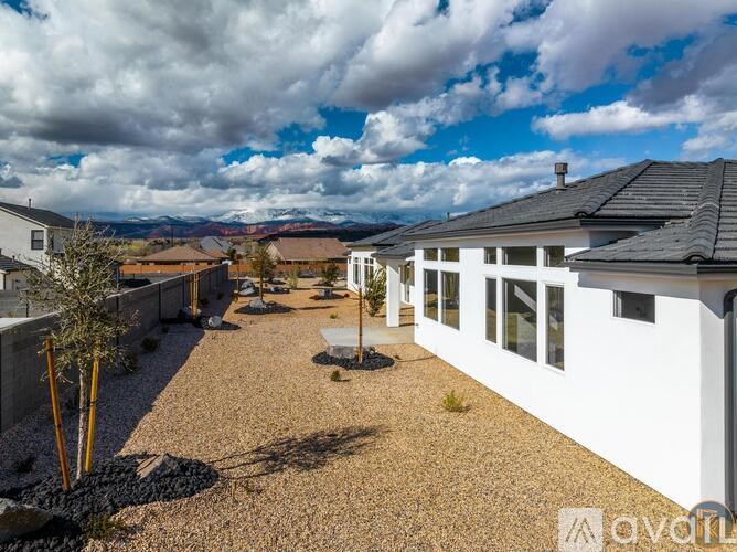 A white house with a gravel yard and a tree in the foreground.