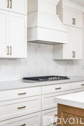 A kitchen with white cabinets and a stove top oven.