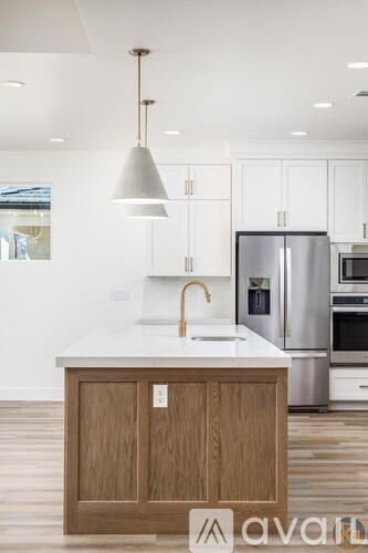 A kitchen with a wooden island and stainless steel appliances.