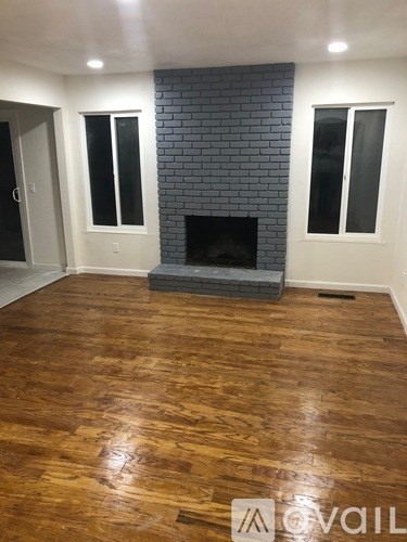 A room with a fireplace and wood flooring.