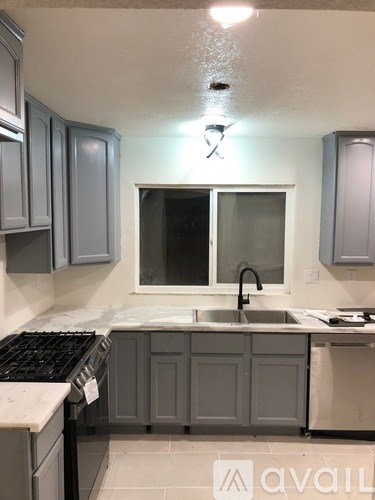 A kitchen with grey cabinets and a white countertop.