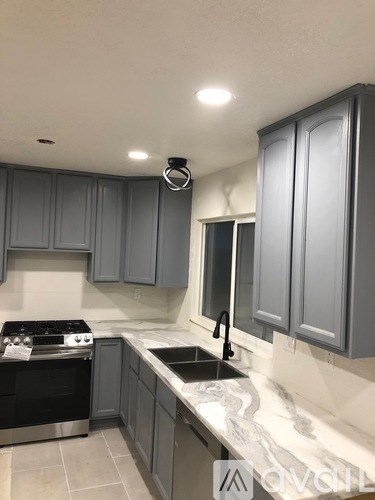 A kitchen with grey cabinets and a black stove top oven.