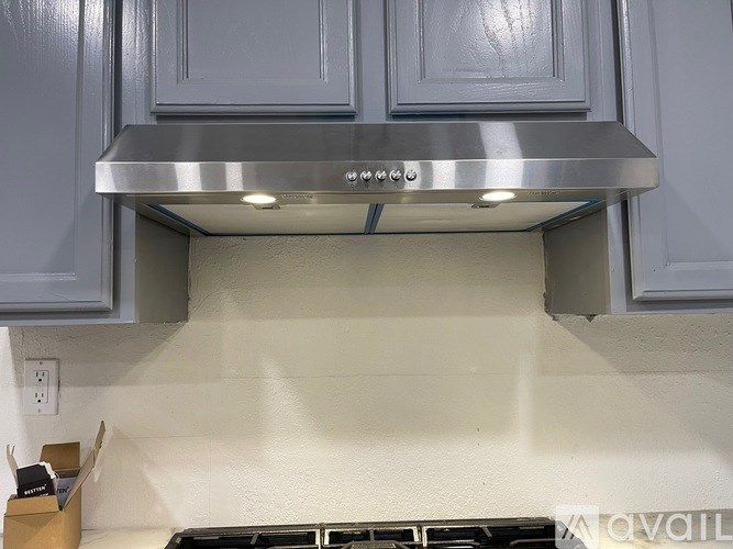 A stainless steel range hood is installed above a stove in a kitchen.