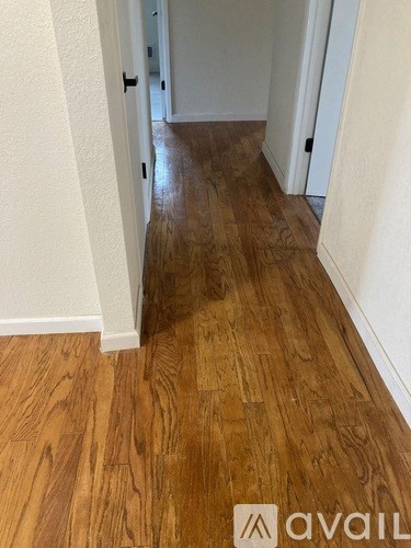 A hallway with wooden floors and white walls.