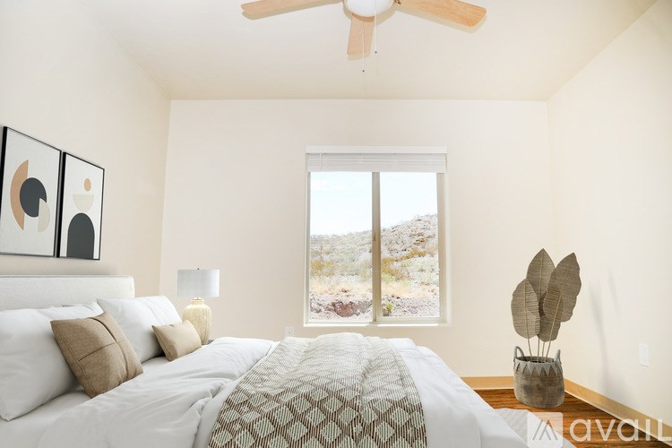 A bedroom with a large bed and a window overlooking a mountainous landscape.