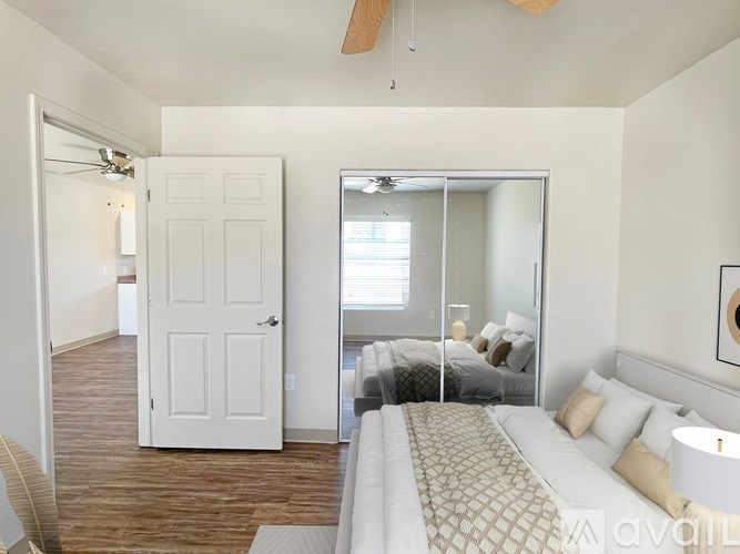 A bedroom with a bed, a ceiling fan, and a mirrored closet door.