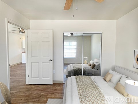 A bedroom with a bed, a ceiling fan, and a mirrored closet door.