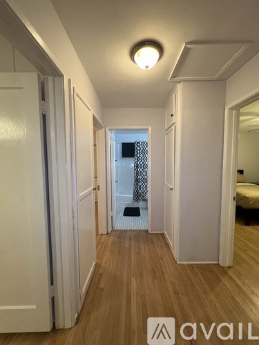 A long hallway with a white door on the left and a mirror on the right.