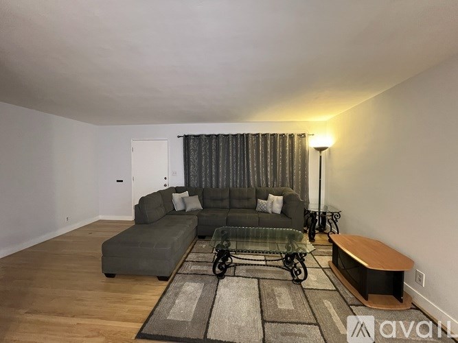 A living room with a grey couch and a glass coffee table.
