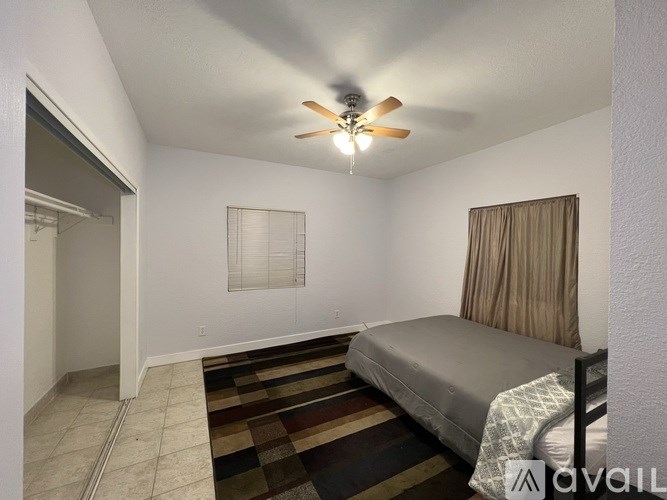 A bedroom with a bed, a ceiling fan, and a rug.