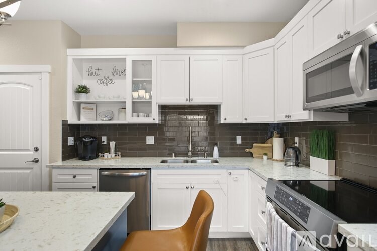 A kitchen with white cabinets and a marble countertop.