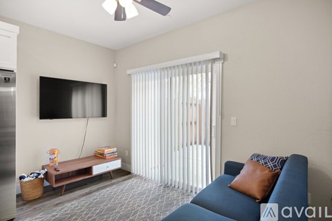 A living room with a blue couch and a television mounted on the wall.