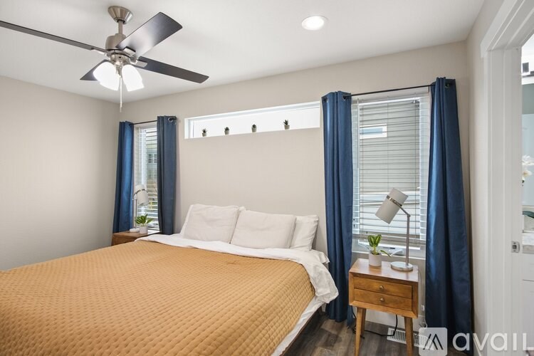 A bedroom with a bed, nightstand, and window with blue curtains.