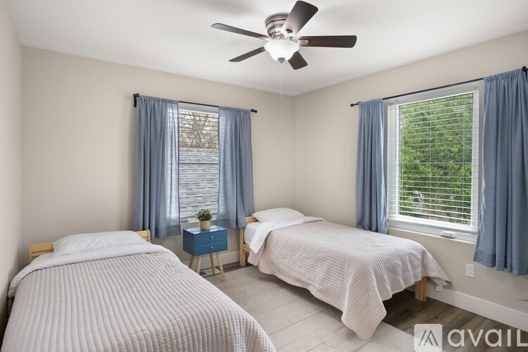 Two twin beds in a room with a ceiling fan.